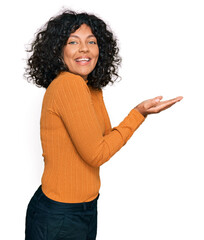 Poster - Young hispanic woman wearing casual clothes pointing aside with hands open palms showing copy space, presenting advertisement smiling excited happy