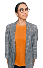 Wall Mural - Young hispanic girl wearing business jacket and glasses smiling looking to the side and staring away thinking.