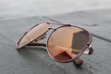 A close up photo of a pair of sunglasses on a wooden bench. 