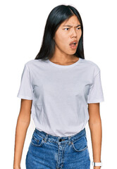 Poster - Beautiful young asian woman wearing casual white t shirt angry and mad screaming frustrated and furious, shouting with anger. rage and aggressive concept.