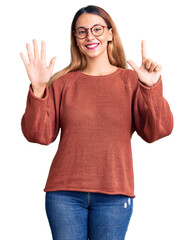 Canvas Print - Beautiful young woman wearing casual clothes and glasses showing and pointing up with fingers number seven while smiling confident and happy.