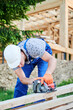 Carpenter using circular saw for cutting wooden plank. Man worker building wooden frame house. The ideology behind modern, environmentally-conscious construction.
