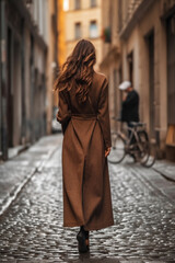 Wall Mural - Lonely woman wearing long brown fancy coat. Autumn casual fashion street style. Back view