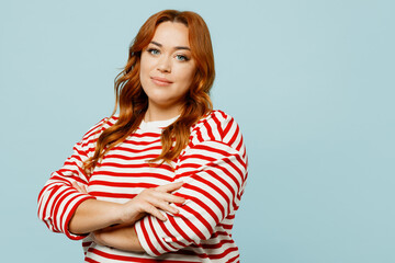 Wall Mural - Side view happy young chubby overweight woman she wearing striped red shirt casual clothes hold hands crossed folded isolated on plain pastel light blue background studio portrait. Lifestyle concept.