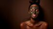 Dark skinned woman stands topless cares about face skin applies nourishing clay mask for rejuvenation does anti wrinkle procedures isolated over green background. Beauty concept copy space