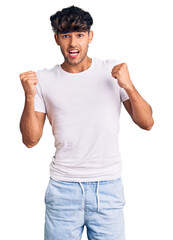 Canvas Print - Young hispanic man wearing casual clothes celebrating surprised and amazed for success with arms raised and open eyes. winner concept.