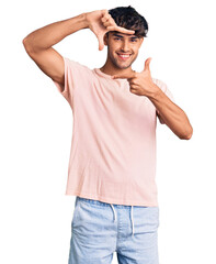 Canvas Print - Young hispanic man wearing casual clothes smiling making frame with hands and fingers with happy face. creativity and photography concept.