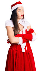 Sticker - Young beautiful caucasian woman wearing santa claus costume looking to the side with arms crossed convinced and confident