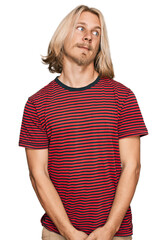 Canvas Print - Caucasian man with blond long hair wearing casual striped t shirt smiling looking to the side and staring away thinking.