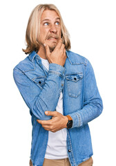 Sticker - Caucasian man with blond long hair wearing casual denim jacket thinking worried about a question, concerned and nervous with hand on chin