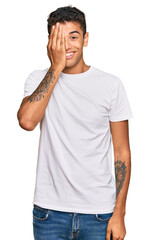 Canvas Print - Young handsome african american man wearing casual white tshirt covering one eye with hand, confident smile on face and surprise emotion.