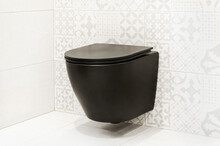 Black Hanging Toilet Against White Wall. Modern Wall Mounted Toilet In A Tiled Bathroom Interior