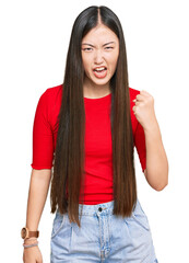 Canvas Print - Young chinese woman wearing casual clothes angry and mad raising fist frustrated and furious while shouting with anger. rage and aggressive concept.