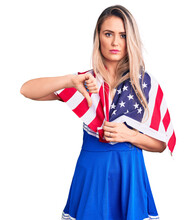Young Beautiful Blonde Woman Wearing Cheerleader Uniform And United States Flag With Angry Face, Negative Sign Showing Dislike With Thumbs Down, Rejection Concept