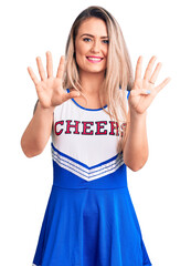 Poster - Young beautiful blonde woman wearing cheerleader uniform showing and pointing up with fingers number nine while smiling confident and happy.