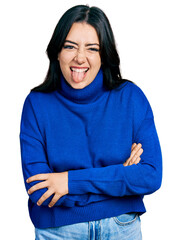 Sticker - Beautiful hispanic woman wearing turtleneck sweater sticking tongue out happy with funny expression.