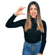 © Krakenimages.com - Young hispanic woman wearing casual clothes smiling and confident gesturing with hand doing small size sign with fingers looking and the camera. measure concept.