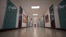 Low Angle Push In Down A Long Empty High School Hallway With US American Flag With The Corridor Lined With Student Lockers.