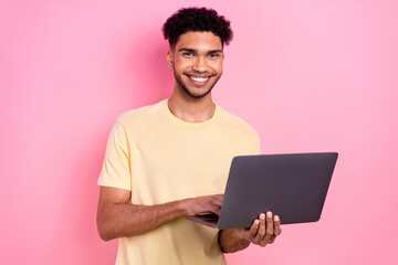 Sticker - Photo of cheerful toothy beaming intelligent guy dressed yellow stylish t-shirt texting email on laptop isolated on pink color background