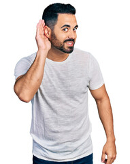 Sticker - Young hispanic man with beard wearing casual grey t shirt smiling with hand over ear listening and hearing to rumor or gossip. deafness concept.