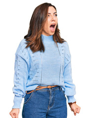 Poster - Young brunette woman wearing casual winter sweater angry and mad screaming frustrated and furious, shouting with anger. rage and aggressive concept.