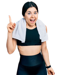 Poster - Young brunette woman with blue eyes wearing sportswear and towel pointing finger up with successful idea. exited and happy. number one.