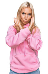 Sticker - Young blonde woman wearing casual sweatshirt rejection expression crossing arms doing negative sign, angry face