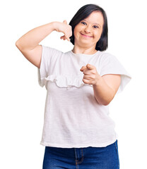 Canvas Print - Brunette woman with down syndrome wearing casual white tshirt smiling doing talking on the telephone gesture and pointing to you. call me.