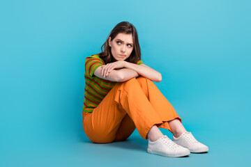 Sticker - Full length photo of minded thoughtful girl curly hairstyle wear striped shirt sitting look empty space isolated on blue color background