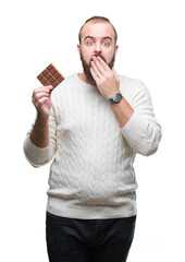 Sticker - Young hipster man eating chocolate bar over isolated background cover mouth with hand shocked with shame for mistake, expression of fear, scared in silence, secret concept