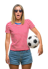 Poster - Young beautiful woman holding soccer football ball over isolated background scared in shock with a surprise face, afraid and excited with fear expression