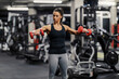 © Dusan Petkovic - A sporty woman is lifting dumbbells in a gym.