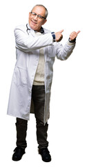 Poster - Handsome senior doctor man wearing medical coat Pointing to the back behind with hand and thumbs up, smiling confident