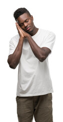 Poster - Young african american man wearing white t-shirt sleeping tired dreaming and posing with hands together while smiling with closed eyes.