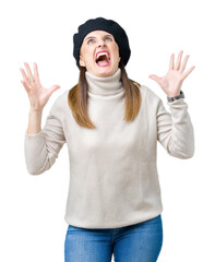 Sticker - Middle age mature woman wearing winter sweater and beret over isolated background crazy and mad shouting and yelling with aggressive expression and arms raised. Frustration concept.