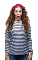 Wall Mural - Beautiful brunette curly hair young girl wearing stripes sweater over isolated background afraid and shocked with surprise expression, fear and excited face.