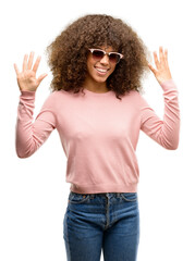 Poster - African american woman wearing pink sunglasses showing and pointing up with fingers number nine while smiling confident and happy.