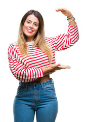 Poster - Young beautiful woman casual stripes winter sweater over isolated background gesturing with hands showing big and large size sign, measure symbol. Smiling looking at the camera. Measuring concept.