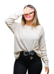 Poster - Young beautiful woman casual white sweater over isolated background smiling and laughing with hand on face covering eyes for surprise. Blind concept.