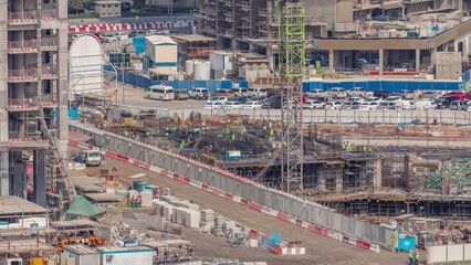 Wall Mural - Large construction site with many working cranes timelapse. Workers creating reinforcement. Top aerial view of big development of residential and office district in Business bay, Dubai