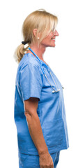 Poster - Middle age blonde nurse surgeon doctor woman over isolated background looking to side, relax profile pose with natural face with confident smile.