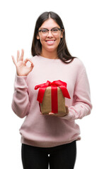 Poster - Young hispanic woman holding a gift doing ok sign with fingers, excellent symbol