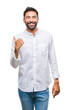 © Krakenimages.com - Adult hispanic man over isolated background smiling with happy face looking and pointing to the side with thumb up.