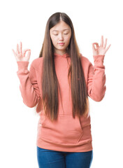 Sticker - Young Chinese woman over isolated background wearing sport sweathshirt relax and smiling with eyes closed doing meditation gesture with fingers. Yoga concept.