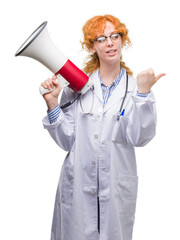 Sticker - Young redhead doctor woman holding megaphone pointing and showing with thumb up to the side with happy face smiling