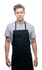 Sticker - Young handsome blond man wearing apron with a confident expression on smart face thinking serious