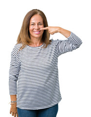 Poster - Beautiful middle age woman wearing stripes sweater over isolated background Pointing with hand finger to face and nose, smiling cheerful