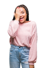 Poster - Young braided hair african american girl wearing sweater over isolated background covering one eye with hand with confident smile on face and surprise emotion.