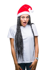 Poster - Young braided hair african american girl wearing christmas hat over isolated background afraid and shocked with surprise expression, fear and excited face.