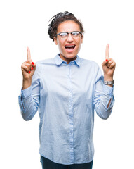 Wall Mural - Young braided hair african american business girl wearing glasses over isolated background amazed and surprised looking up and pointing with fingers and raised arms.